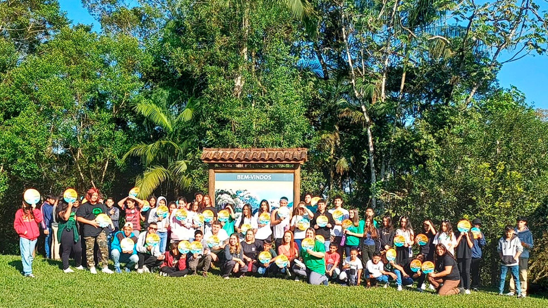 Imagens de jovens olhando para a câmera sentados na grama.